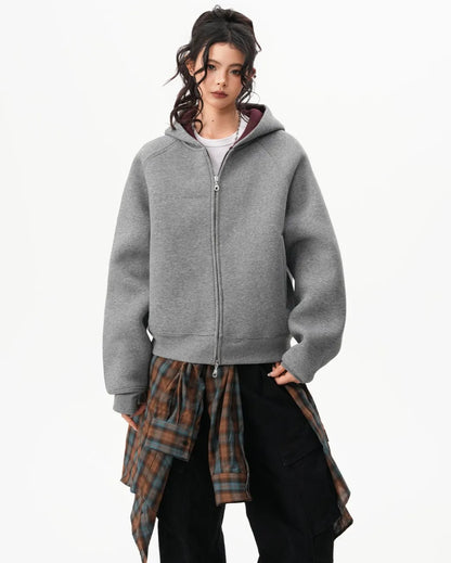 チェックシャツを腰に巻いたモデルがグレーのラグランジップパーカーをファスナー全閉で着用している正面写真