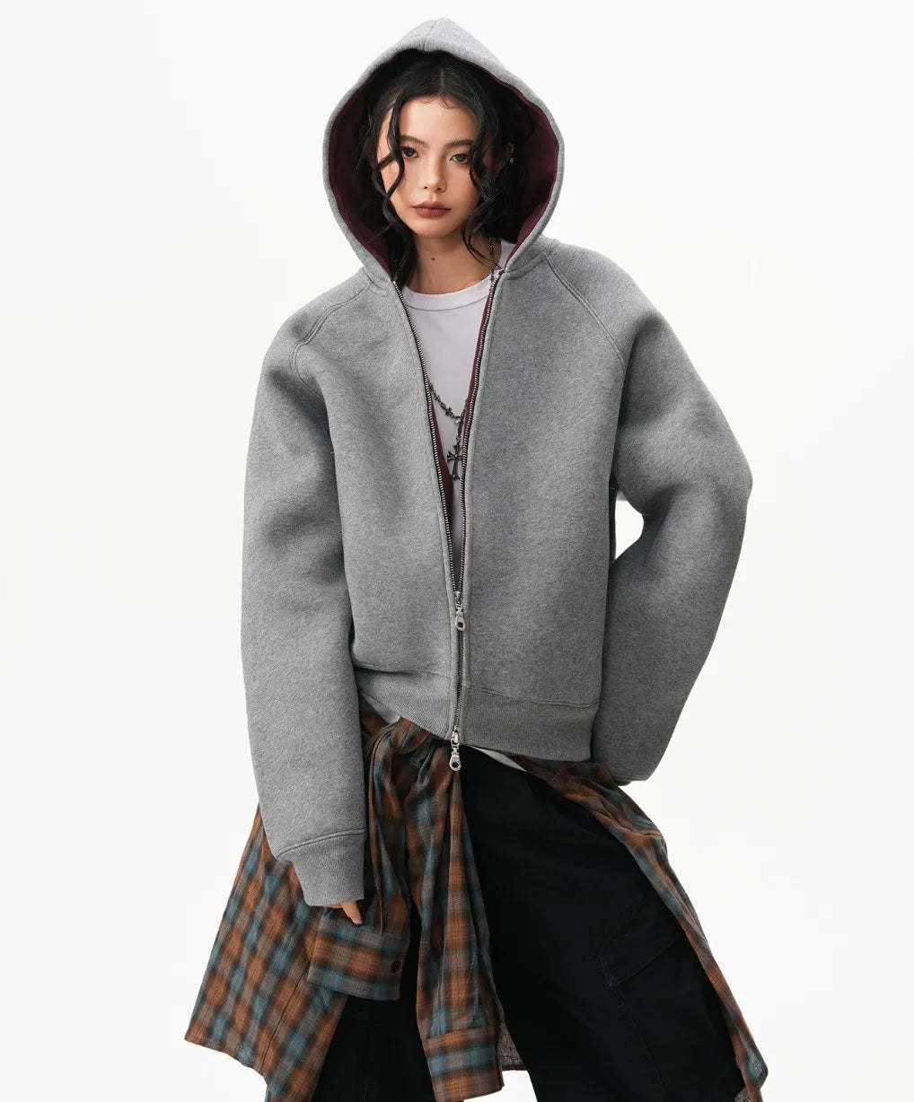 フードをかぶったモデルがグレーのラグランジップパーカーと腰巻きチェックシャツを合わせたスタイリング写真