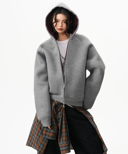 フードをかぶったモデルがグレーのラグランジップパーカーと腰巻きチェックシャツを合わせたスタイリング写真