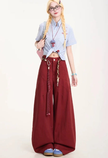 バーガンディカラーのバルーンパンツを着用した立ち姿。ブルーのギンガムチェックシャツとのコーディネート。