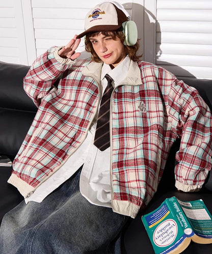 赤チェック柄側のリバーシブルジャケットを着たモデル。ソファで本を読む。