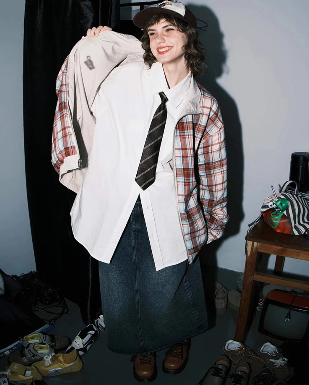 赤チェック柄側のリバーシブルジャケットを裏返しているモデル。笑顔。