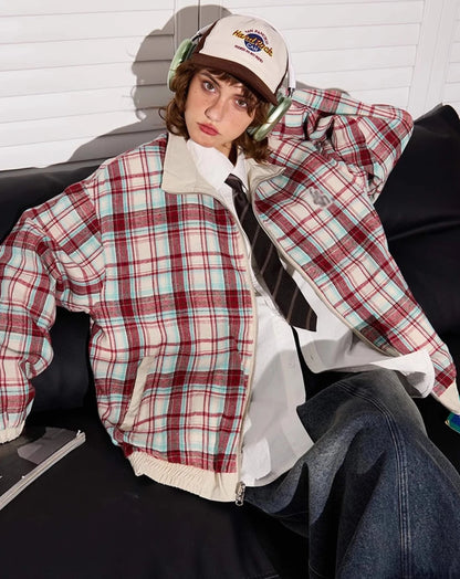 赤チェック柄側のリバーシブルジャケットを着たモデル。ソファに座り、少し憂いを帯びた表情。