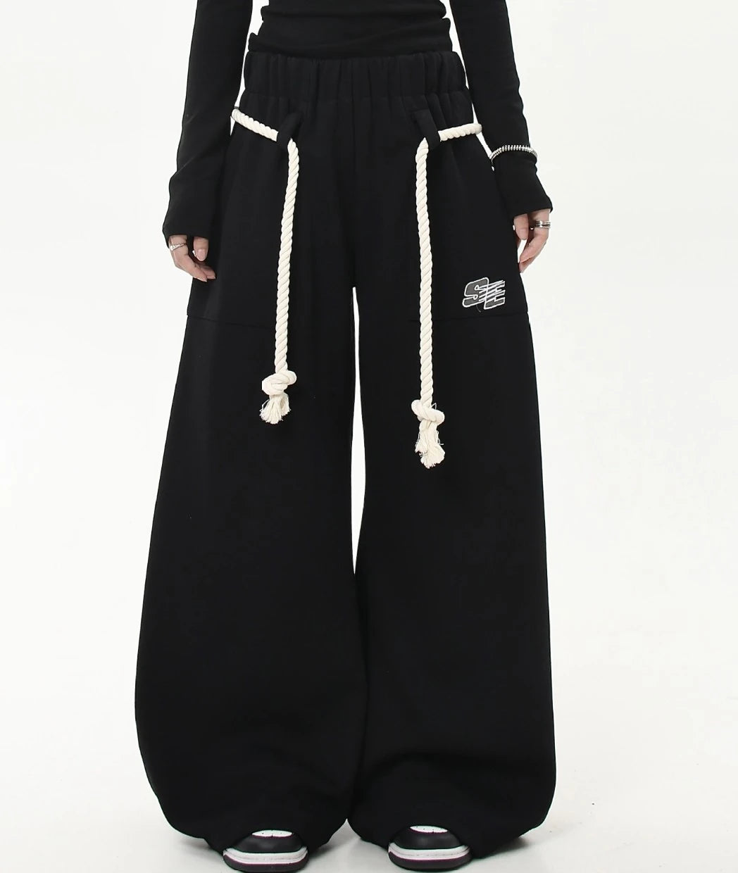 太めのホワイトロープベルトがポイントのブラックワイドスウェットパンツ正面ショット。裾まで広がるゆったりシルエットが分かる画像。