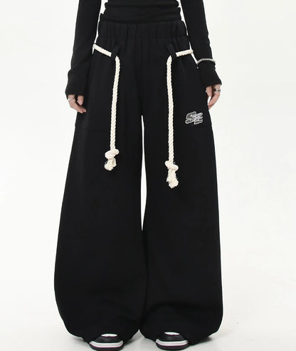 太めのホワイトロープベルトがポイントのブラックワイドスウェットパンツ正面ショット。裾まで広がるゆったりシルエットが分かる画像。