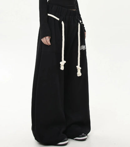 ロープベルトとロゴパッチが付いたブラックワイドスウェットパンツの斜めフロントショット。腰回りのディテールが分かりやすい。