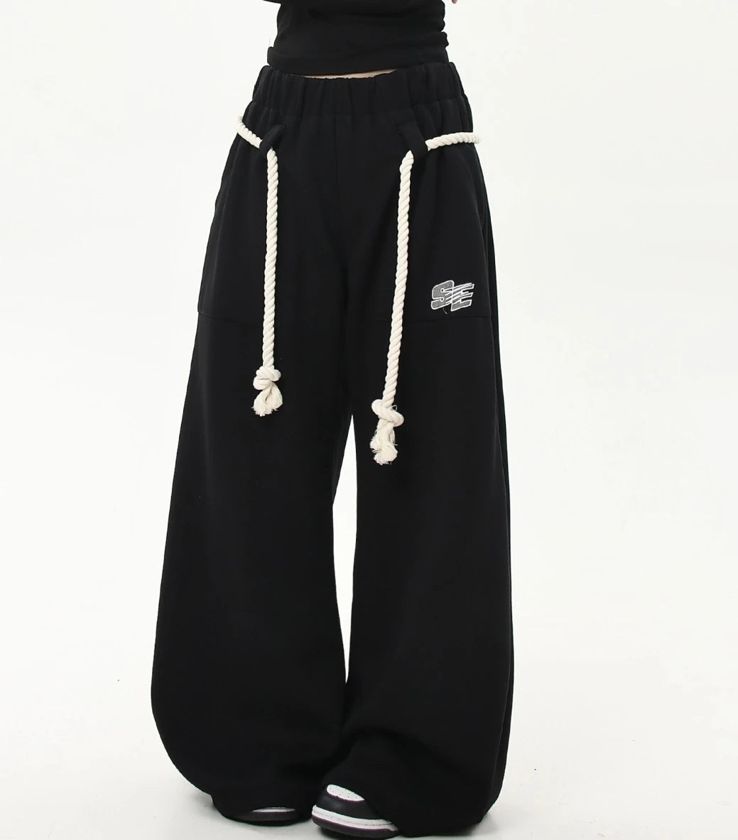 ロープベルトをラフに垂らしたブラックワイドスウェットパンツの正面スタイリング画像。カジュアルストリートな雰囲気の一本。