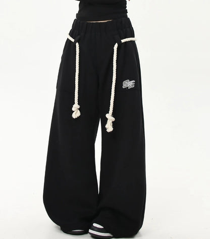 ロープベルトをラフに垂らしたブラックワイドスウェットパンツの正面スタイリング画像。カジュアルストリートな雰囲気の一本。