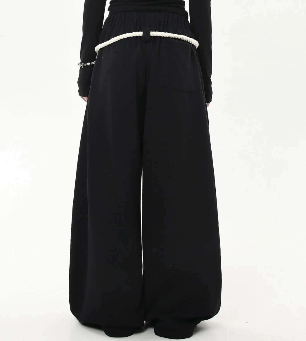 ウエスト周りにロープベルトを回したブラックワイドスウェットパンツのバックショット。ヒップから裾までまっすぐ落ちるワイドラインが見える。