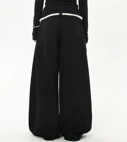 ウエスト周りにロープベルトを回したブラックワイドスウェットパンツのバックショット。ヒップから裾までまっすぐ落ちるワイドラインが見える。