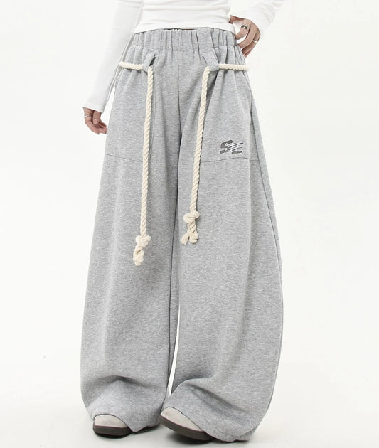 ウエストにホワイトロープベルトを巻いたグレーワイドスウェットパンツのバックショット。ヒップから裾までまっすぐ落ちるワイドシルエットが分かる。
