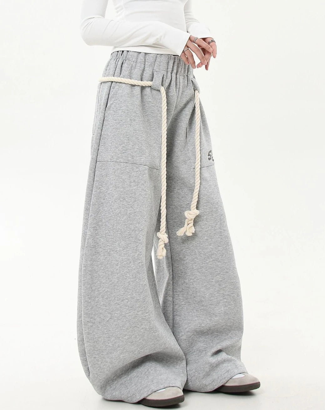 斜め前から撮影したグレーワイドスウェットパンツ。腰回りをぐるりと囲むロープベルトとワイドなラインが強調されたカット。