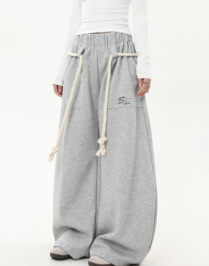 ロープベルトをラフに垂らしたグレーワイドスウェットパンツの斜めフロントショット。カジュアルでリラックス感のあるスタイリング画像。