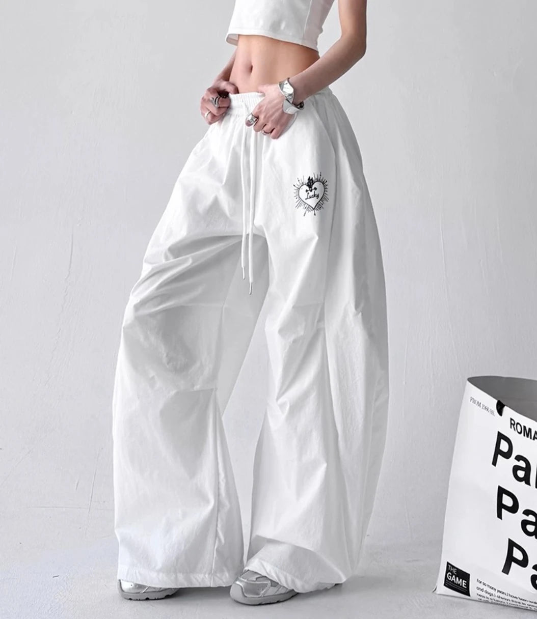 ホワイトのバルーンパンツの斜めアングル。ウエストのドローコードとサイドのボリューム感が際立つアングル。