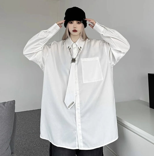 白のオーバーサイズシャツを着用し、黒いニット帽に手を添えたポーズ。シルバーのチェーンアクセサリーがアクセントのストリートスタイル。