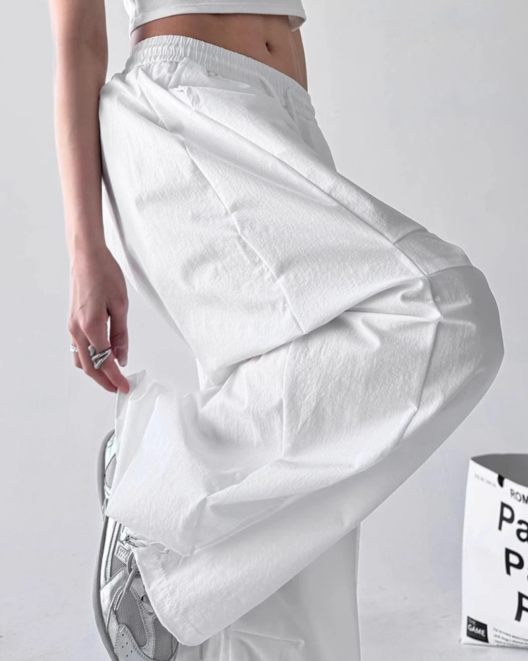 パンツのサイドビューと生地の質感。膝部分のタックデザインと、足を上げた際の立体的なボリューム感。