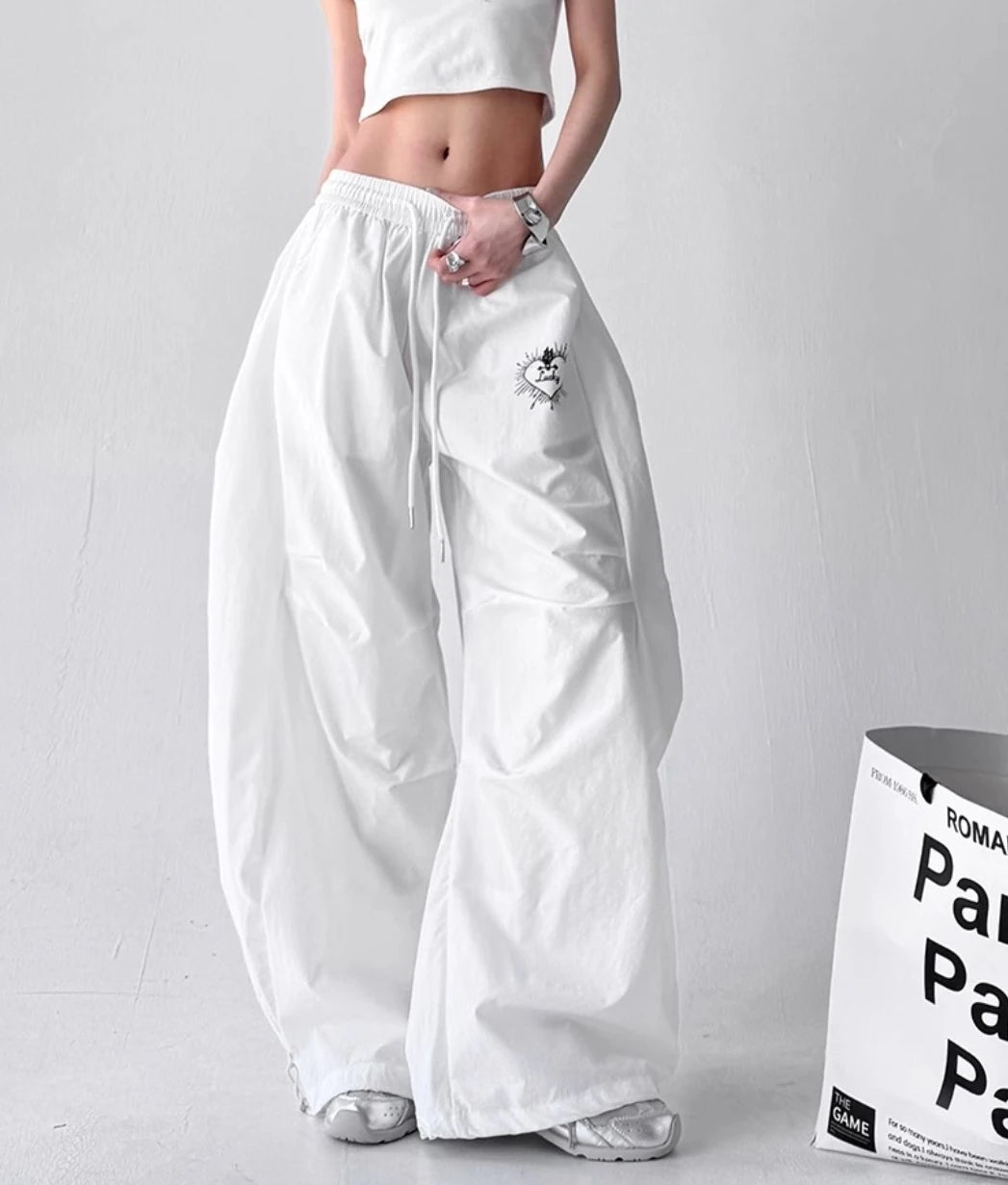 白のパラシュートパンツを着用した全身写真。ゆったりとしたワイドシルエットとストリートスタイルのコーディネート。